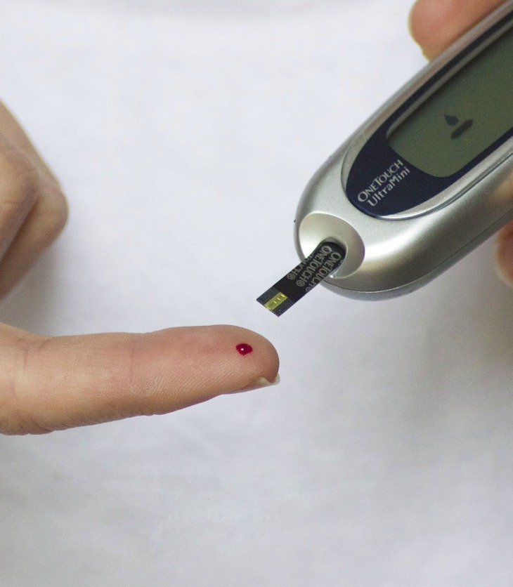 Manos de una persona midiendo su glucosa con un glucómetro