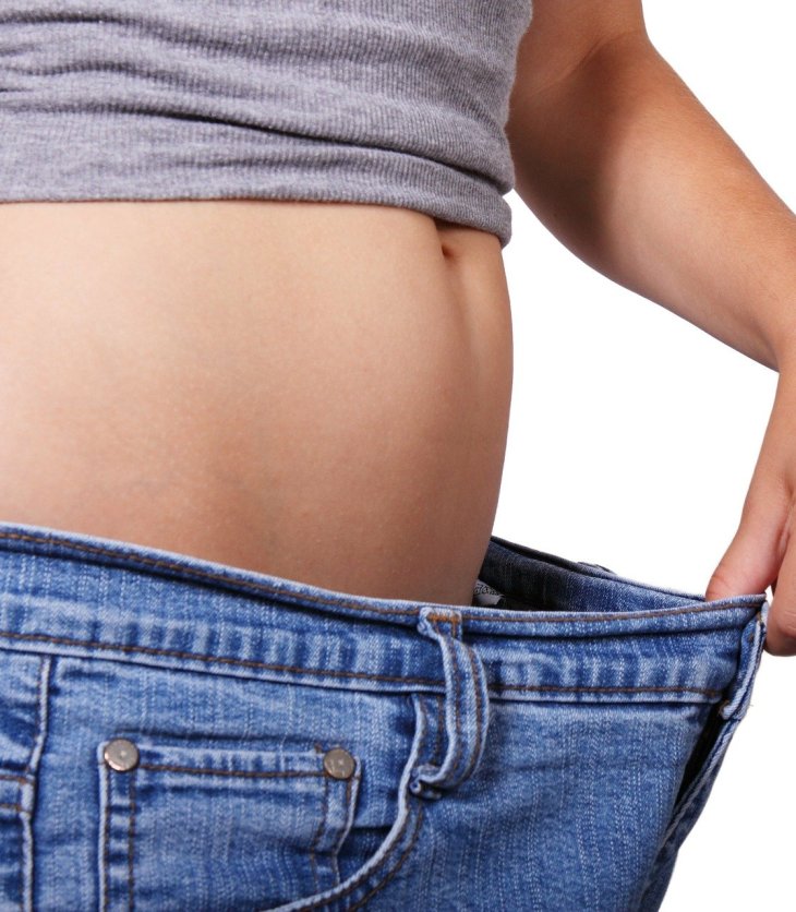 Mujer que ha bajado de peso muestra un pantalón que le queda grande en la cintura