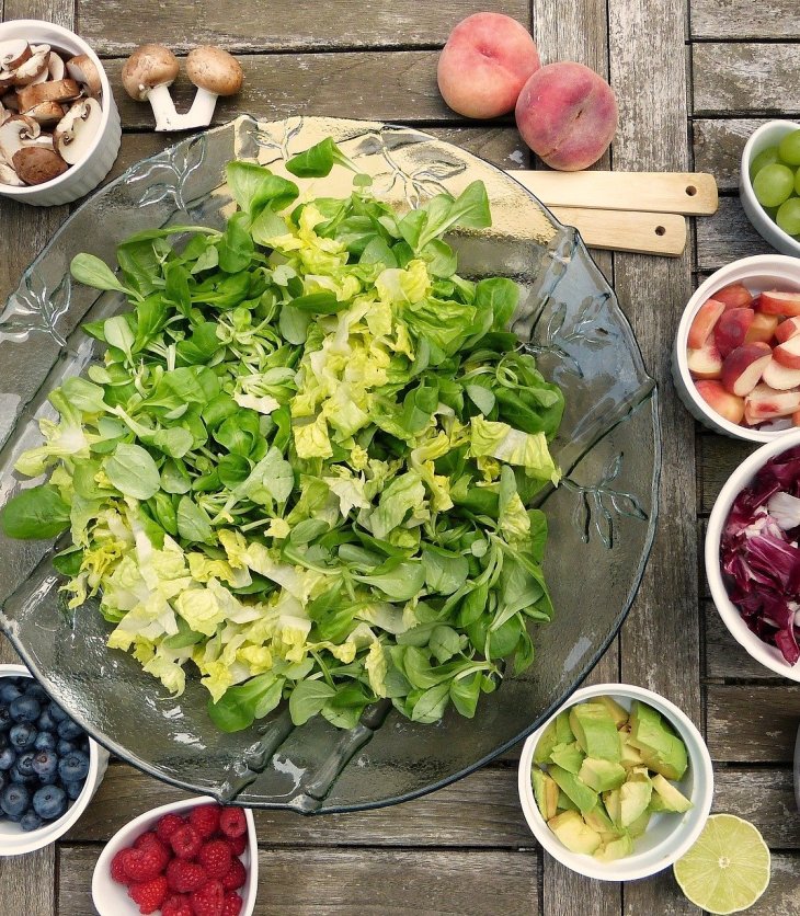 Tazones de diferentes tamaños con ingredientes para preparar ensalada de verduras y frutas